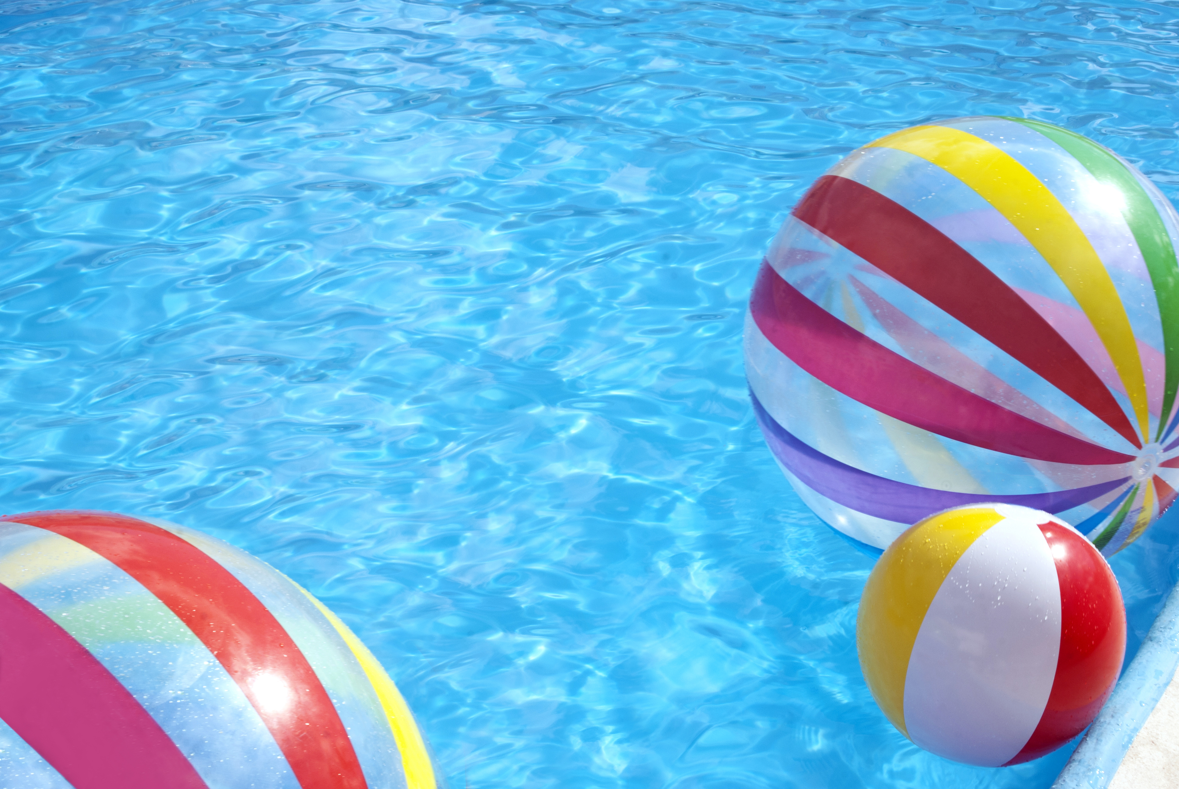 Three beach balls floating in a pool