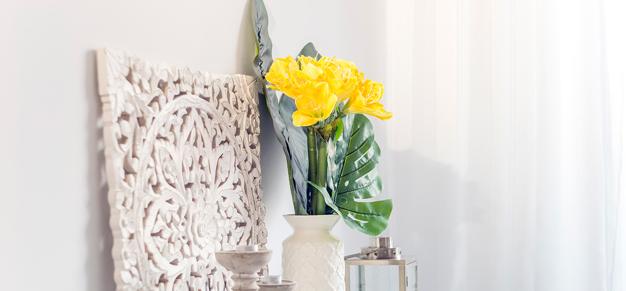 yellow flowers in ceramic vase with wooden candlesticks and lantern decorating a shelf