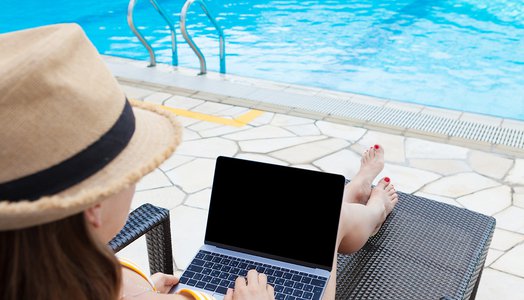 Young woman using laptop near a swimming pool